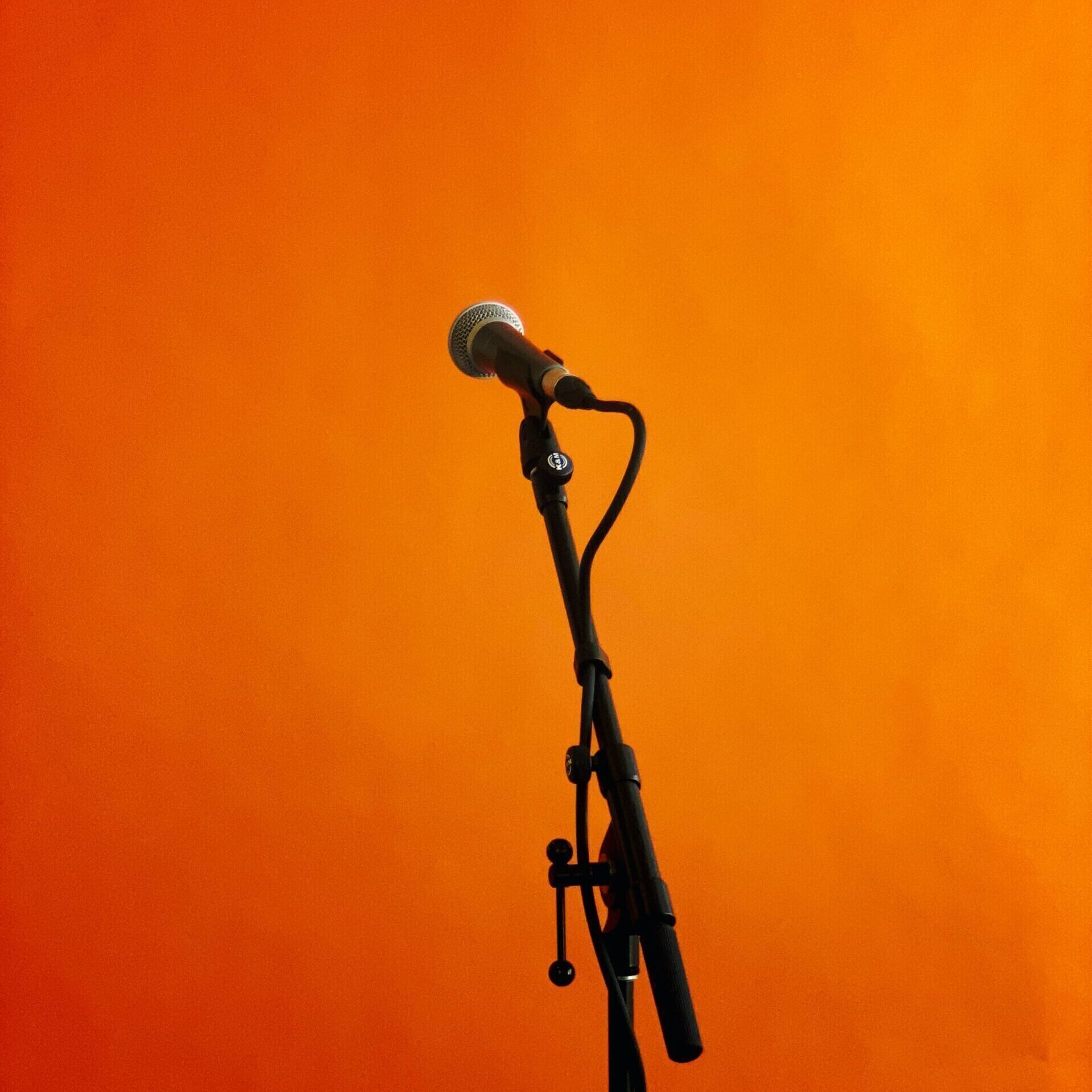 Black microphone and stand on orange background